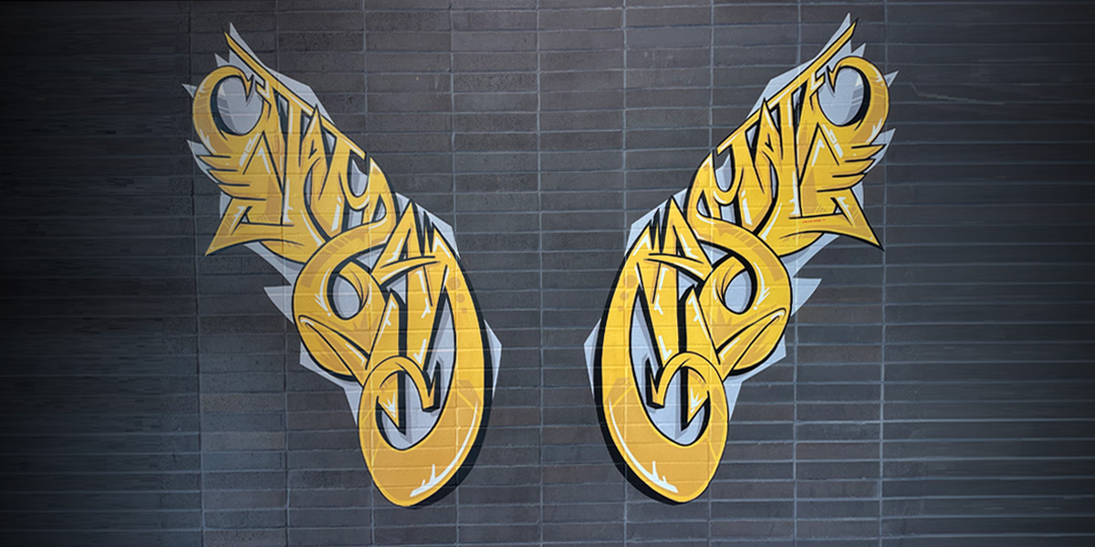 Artistic interpretation of wings on a black brick wall inside of the Cal State LA student services building.