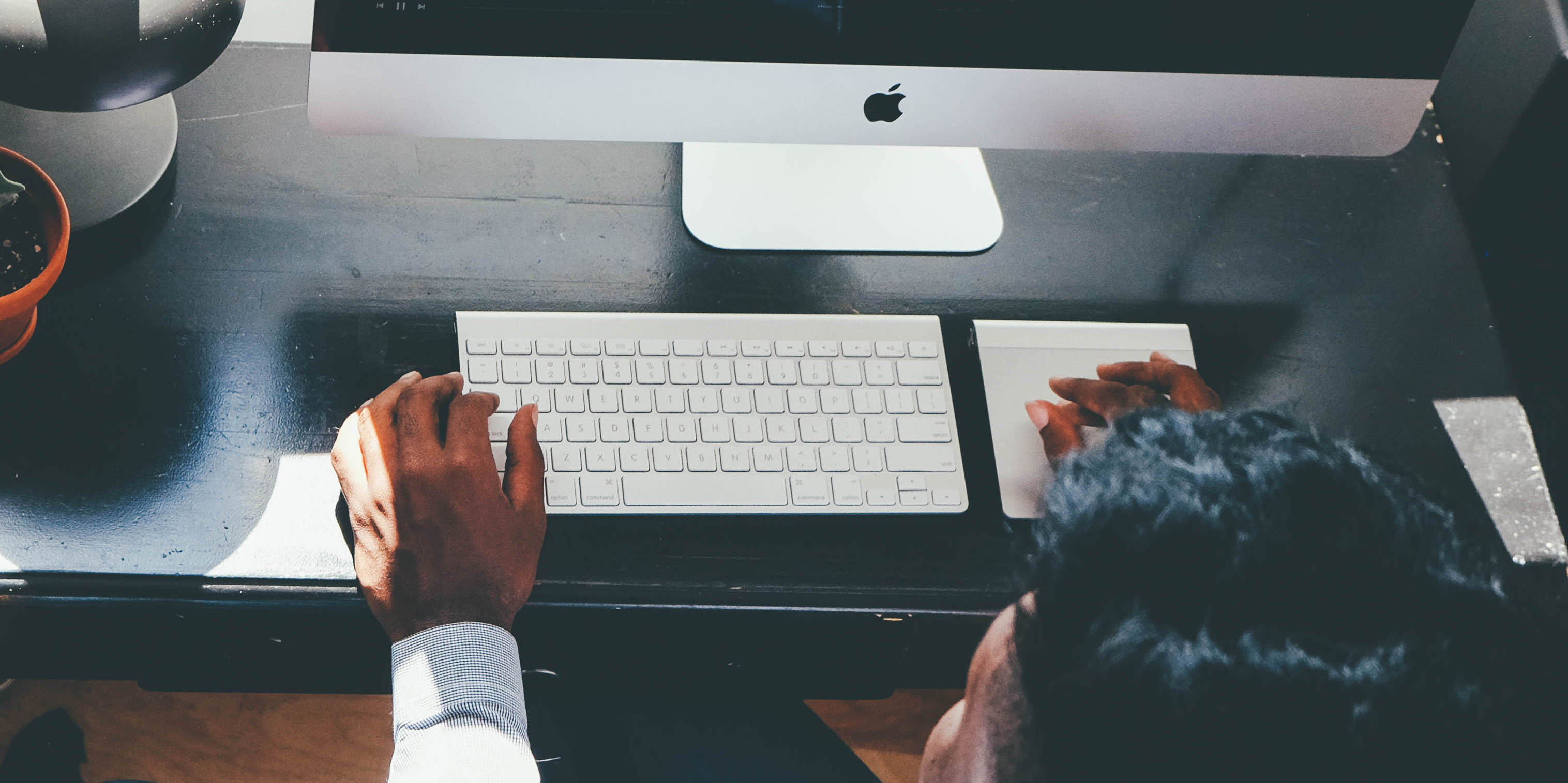 Person at desk with hands on computer keyboard