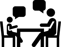 Silhouette of two people sitting at a table having a conversation.