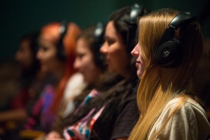 A seated row of students in an audio production class, each wearing headphones.