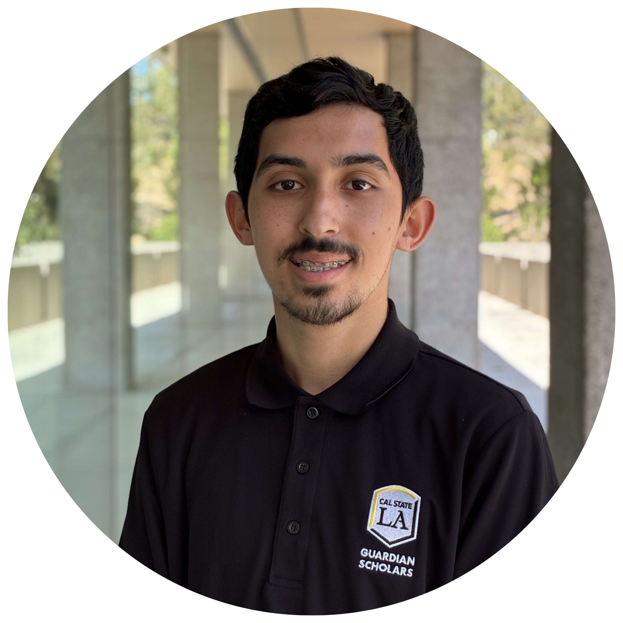 Jesus Ornelas, the student assistant at Cal State LA, smiling and wearing a black Cal State LA Guardian Scholars polo shirt