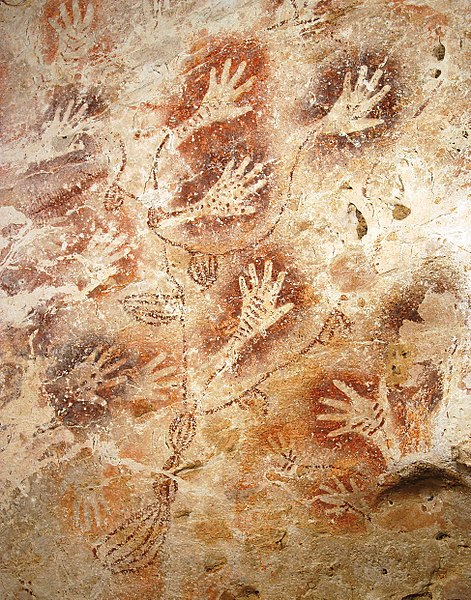 A rock art mural with a series of hands and branch-like lines 