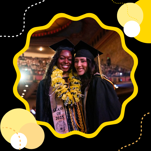 Two graduates wearing their cap and gown smiling and posing together