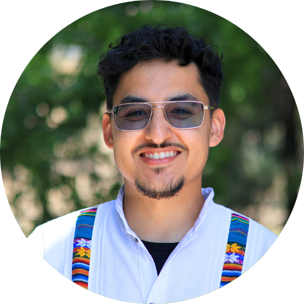 A man with black hair and sun glasses smiling wearing a white shirt.