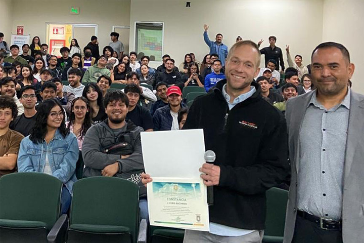 Dr Bachman holds certificate with class behind