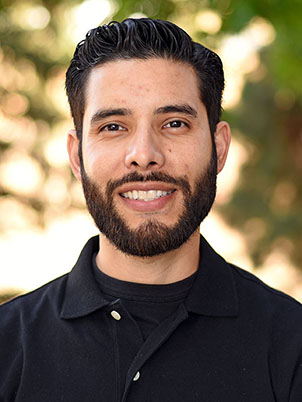 A person with short hair and beard smiling.