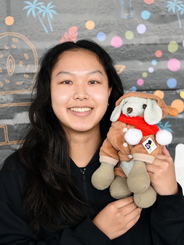 A person with long hair smiling and holding a plushy