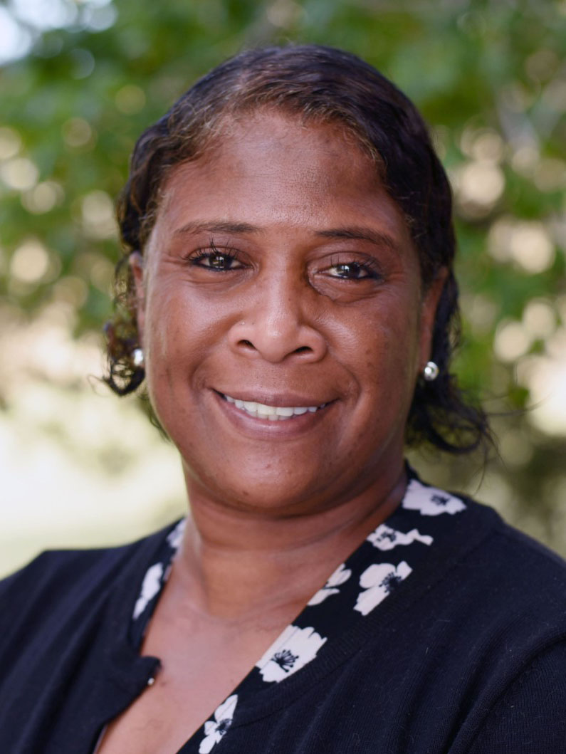 A person with short hair, wearing earrings, smiling.