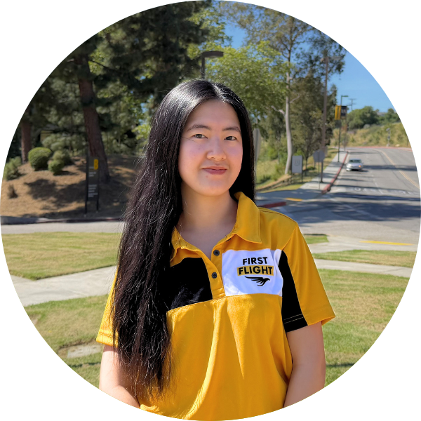 A woman with long black hair and a Yellow polo smiling.
