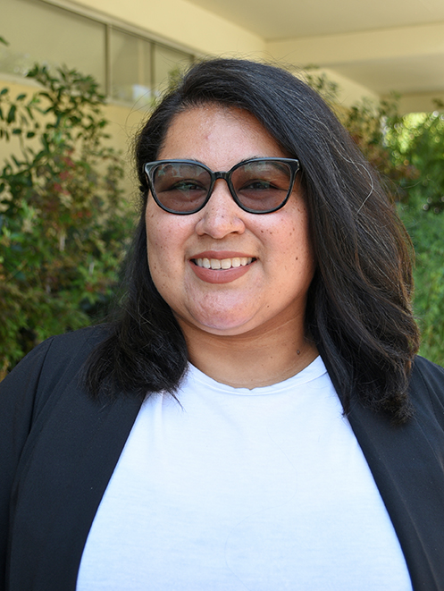 A person with long hair wearing sunglasses and smiling.