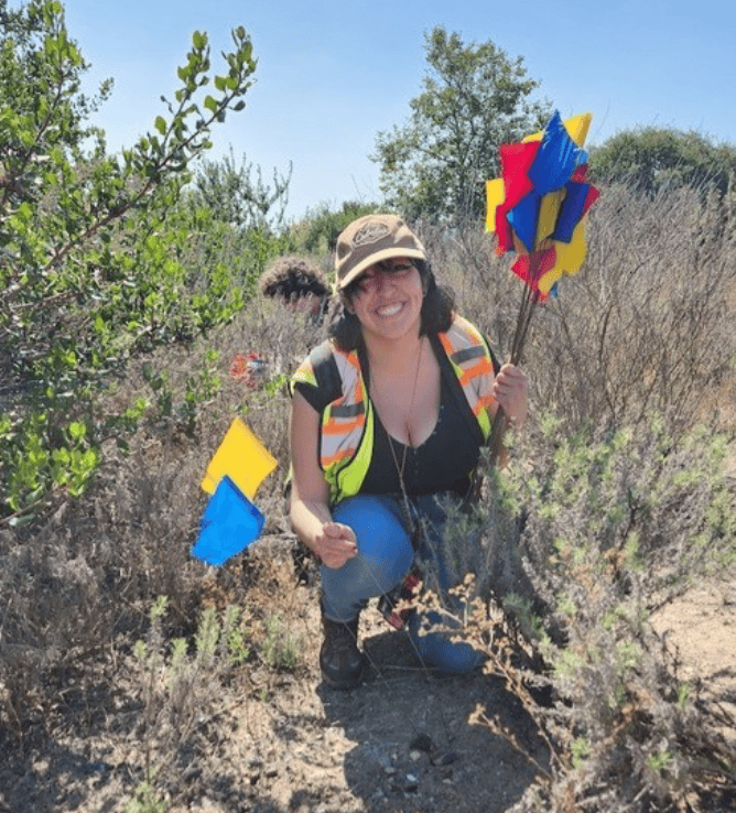 Grad Student holding multicolored flags in the field