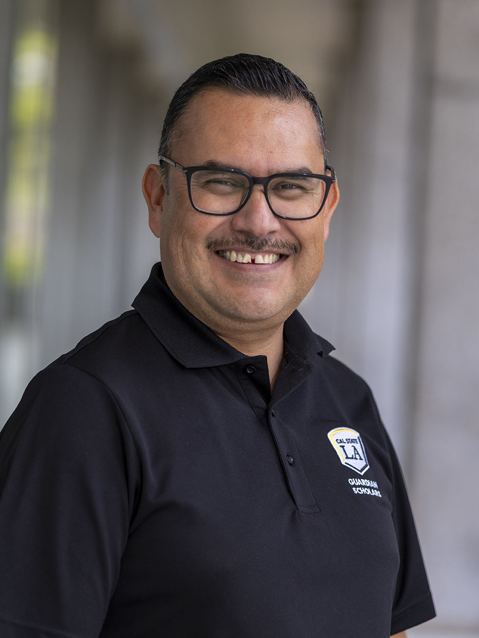 A person with short hair and glasses smiling.