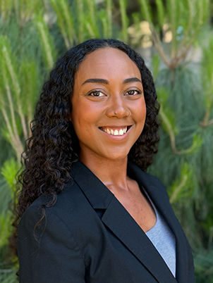 A person with long, curly hair and a big smile.