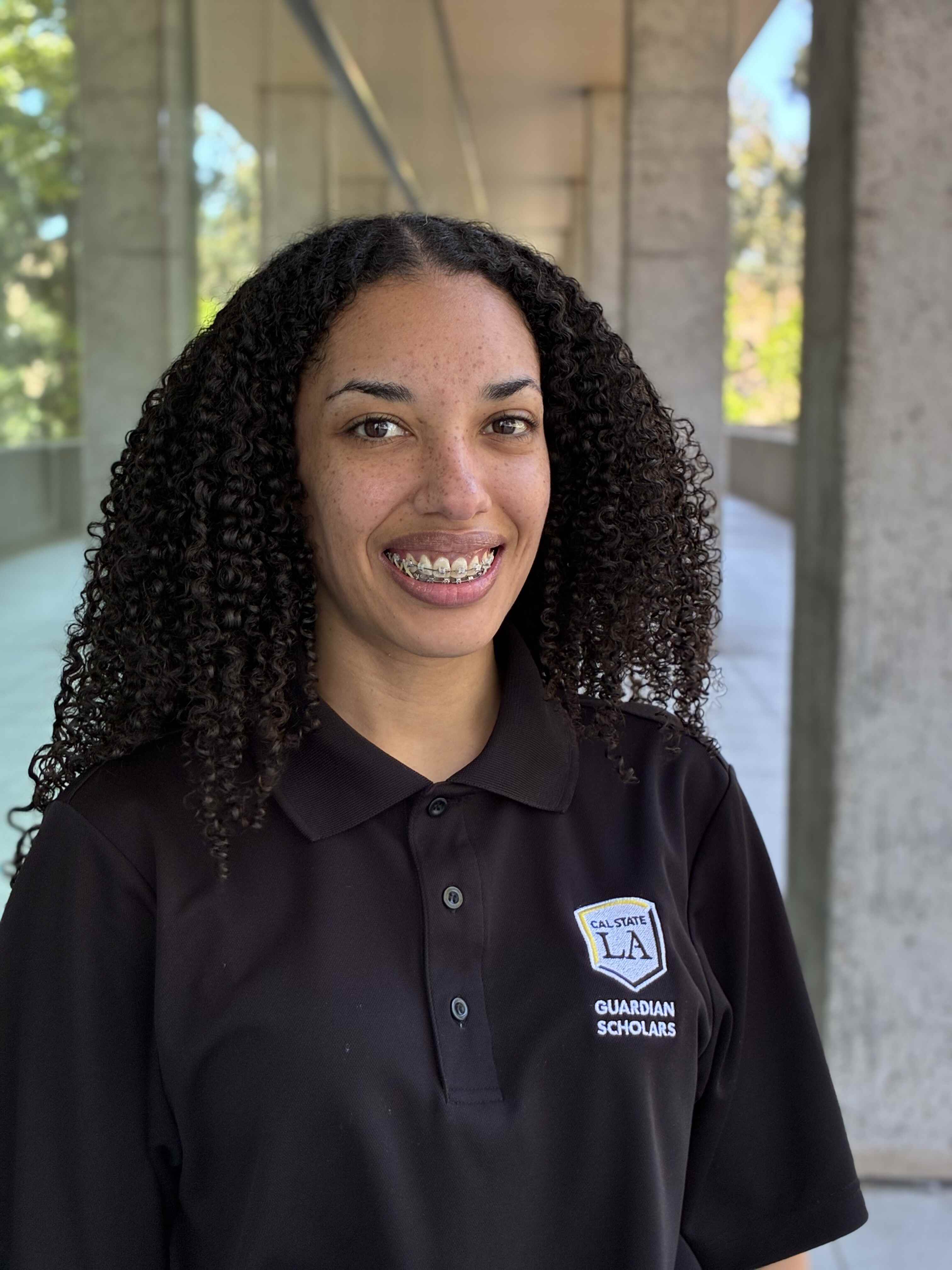Kely Taylor, a peer mentor at Cal State LA, smiling and wearing a black Cal State LA Guardian Scholars polo shirt
