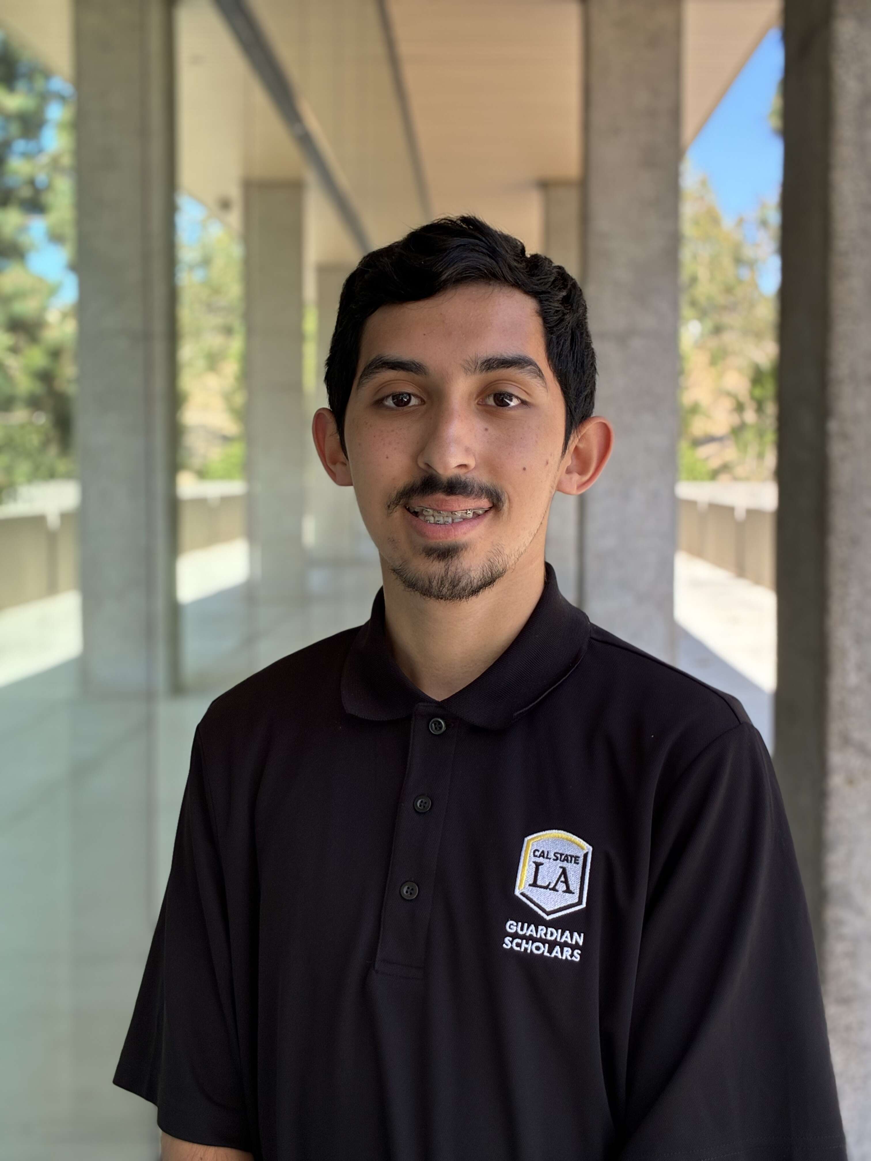 Jesus Ornelas, the student assistant at Cal State LA, smiling and wearing a black Cal State LA Guardian Scholars polo shirt