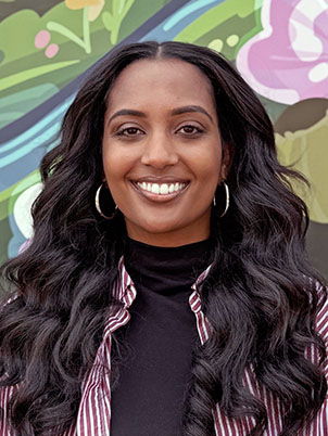 A person with long wavy hair smiling.