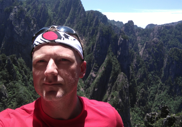 a person in a red shirt taking a selfie in front of mountains
