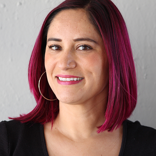 A person with shoulder-length hair smiling.