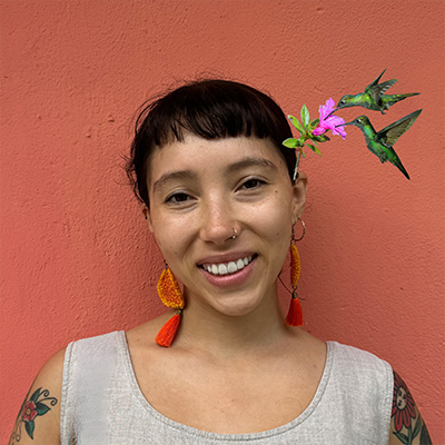 Jessica Santos with a flower in her head posing in front of a wall