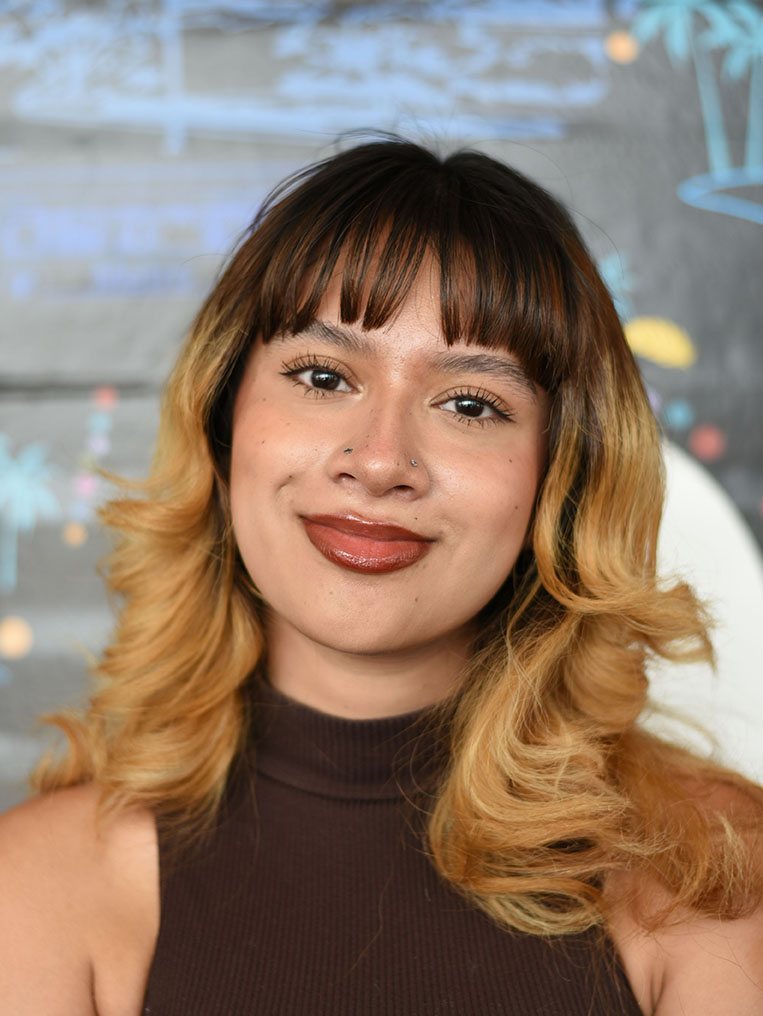 A person with shoulder-length wavy hair smiling.
