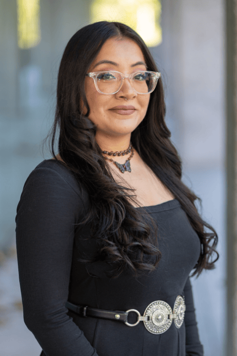 A person with shoulder-length hair and glasses smiling.