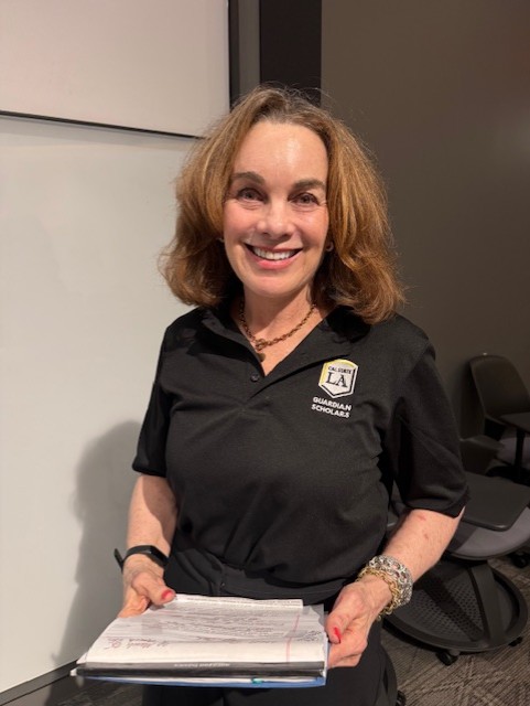 Phone of woman in black shirt with medium length hair holding a clipboard