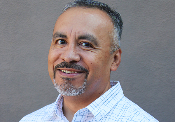 A person with salt-and-pepper facial hair smiling