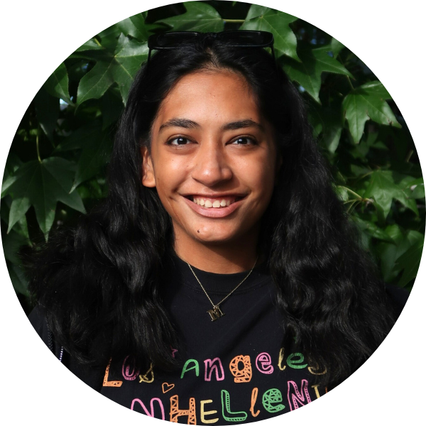 Woman with black t-shirt smiling in front of leaves.