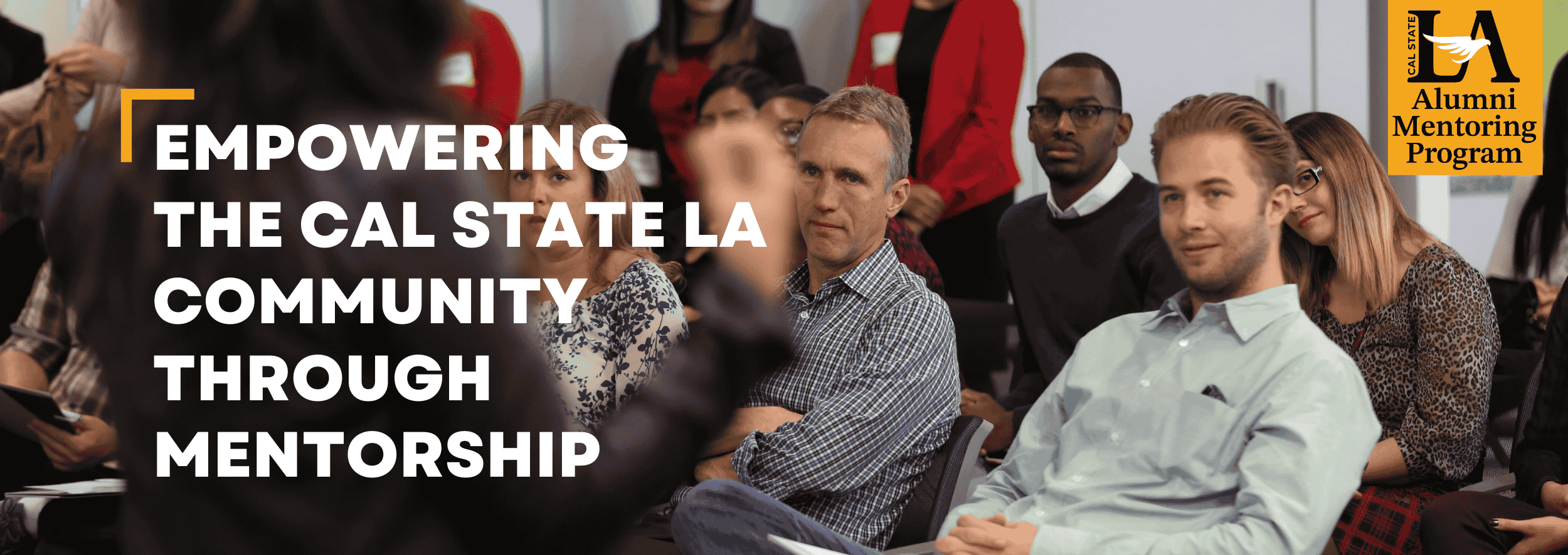 Group of people sitting in chairs watching a speaker at the front of the room. Overlaid text reads: Empowering the Cal State L.A. community through mentorship
