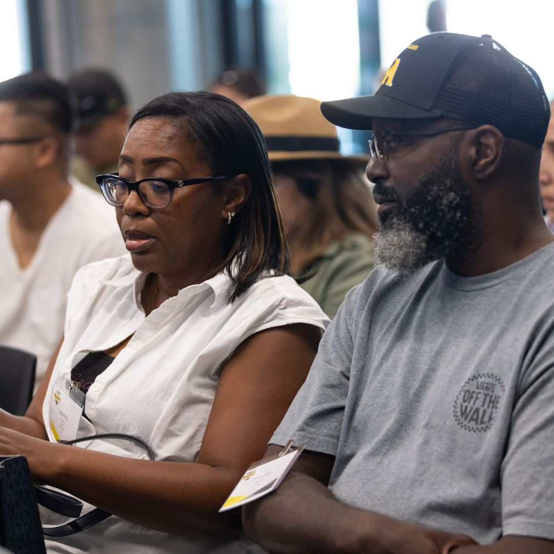 A man and woman looking down at their phone