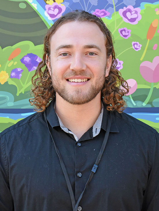 A person with curly hair and facial hair smiling.