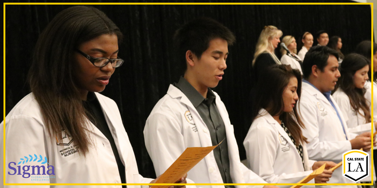 Cal State LA nursing students standing in a line holding a pieces of paper reciting an oath