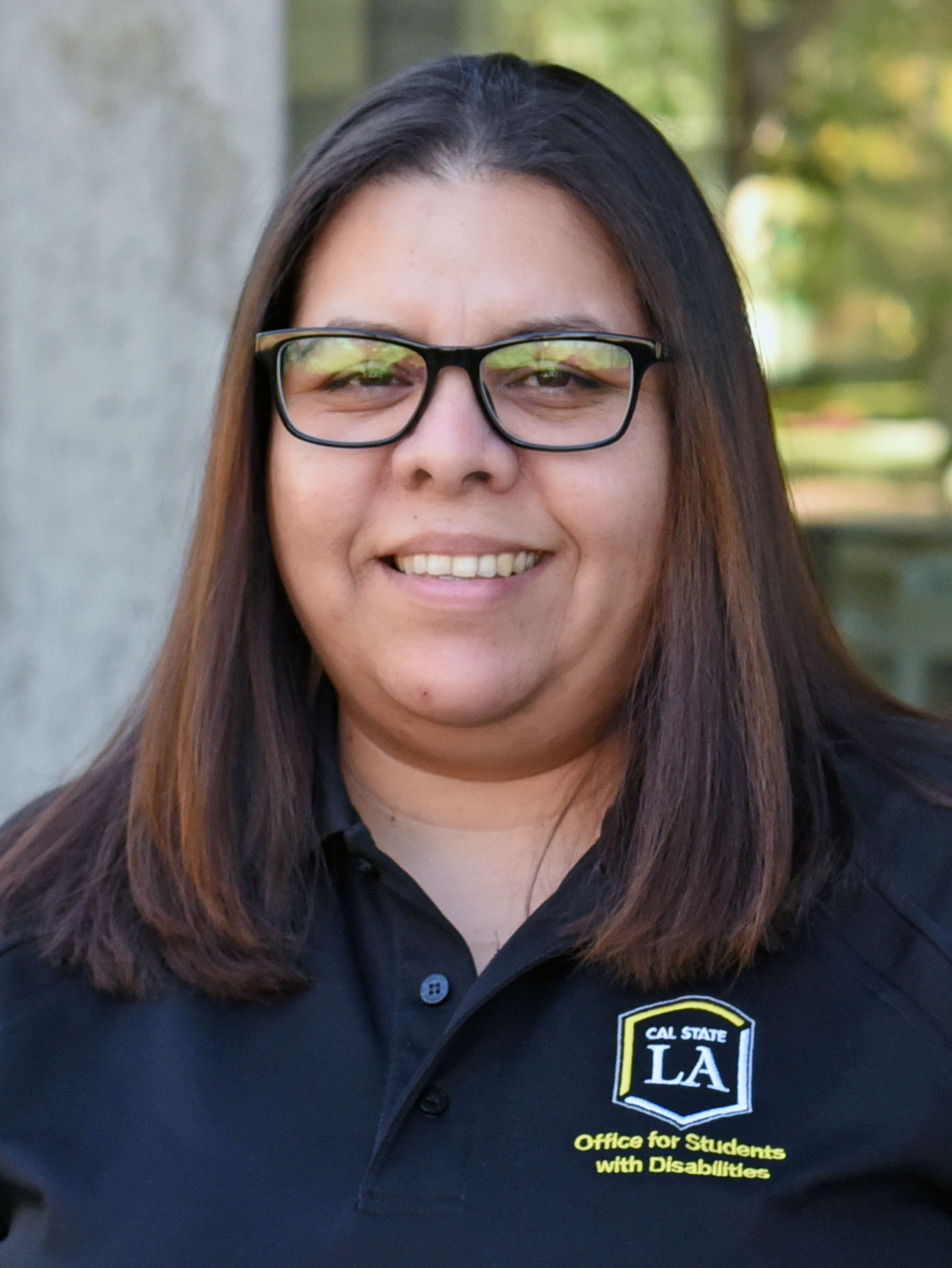 A person with should-length hair, wearing glasses and smiling.