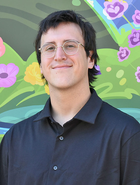 A person with short hair and glasses smiling slightly.