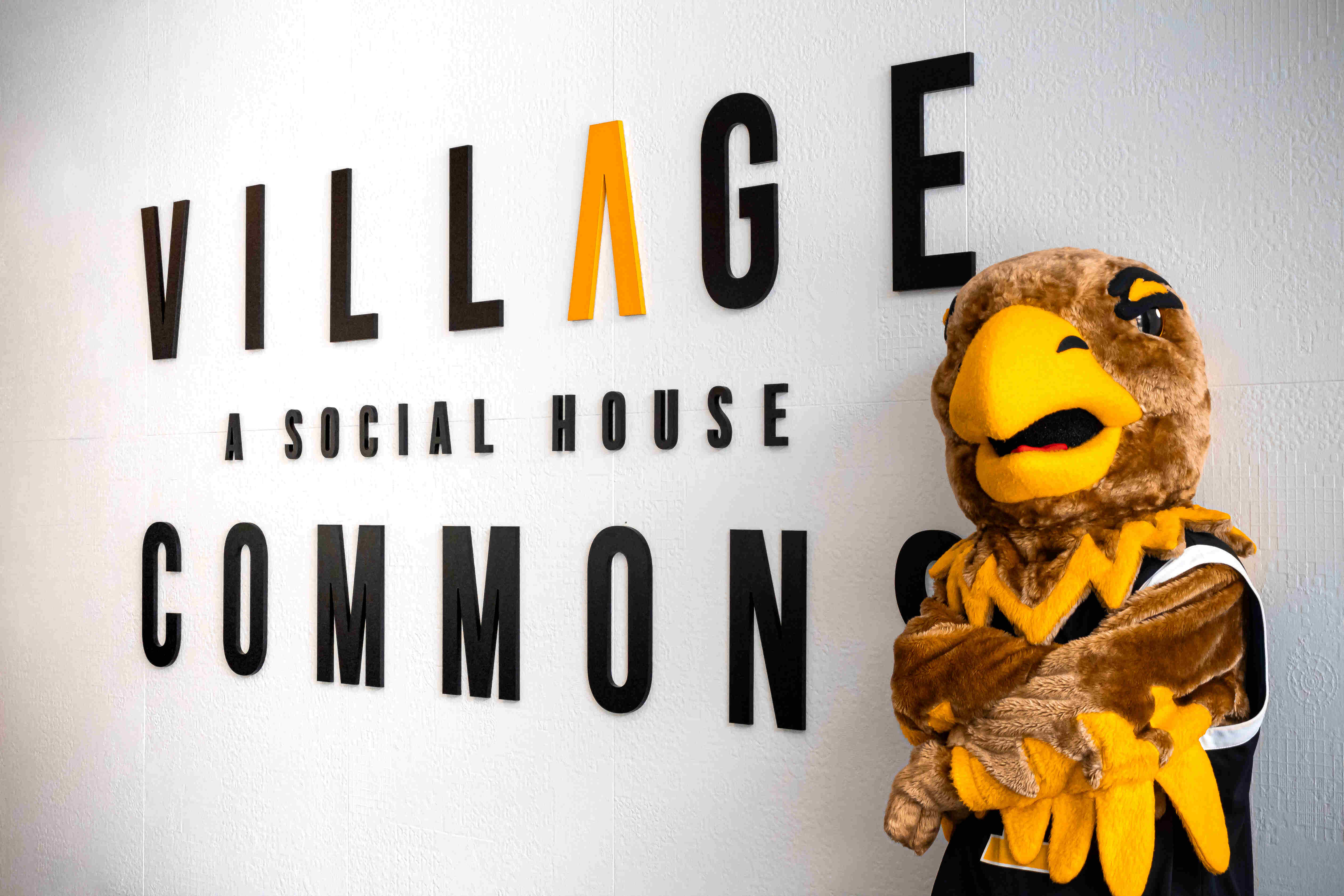 Village Commons. A social house. Eddie the Golden Eagle posing next to the sign.
