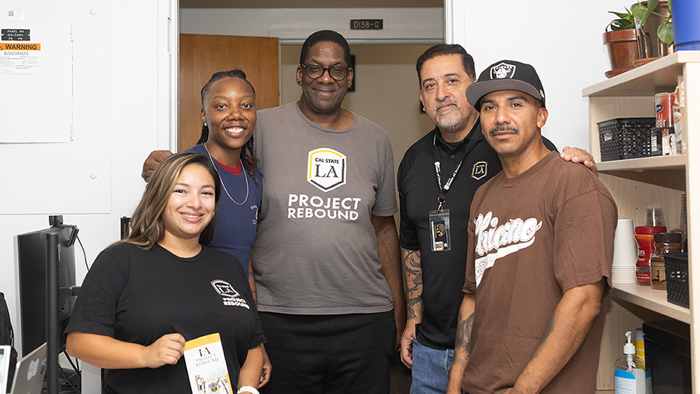 A group of five people standing together smiling.