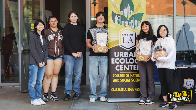 A group of six students standing in front of a banner that reads "Cal State LA Urban Ecology Center" holding awards