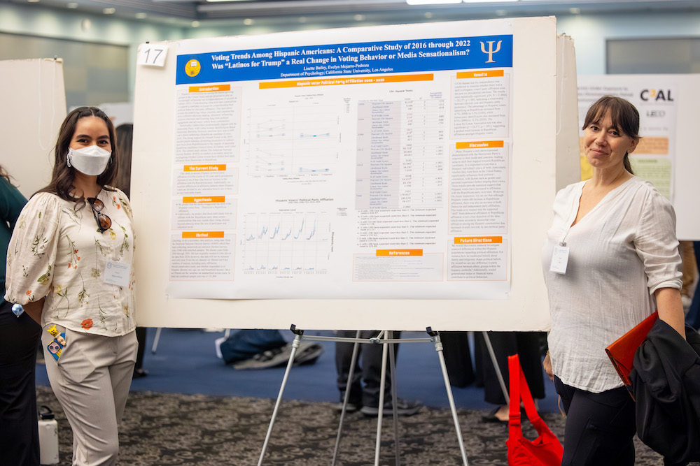 Two people standing next to a poster