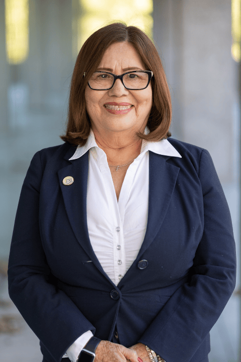 A person with shoulder-length hair and glasses smiling.