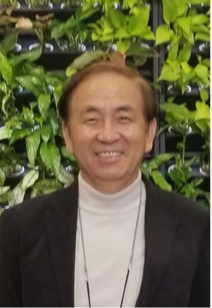 Simon C. Kim smiling in front of plants