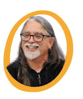 Smiling older man with long gray hair, glasses, and a white goatee, wearing a black jacket and a small hoop earring, framed by a yellow oval border.