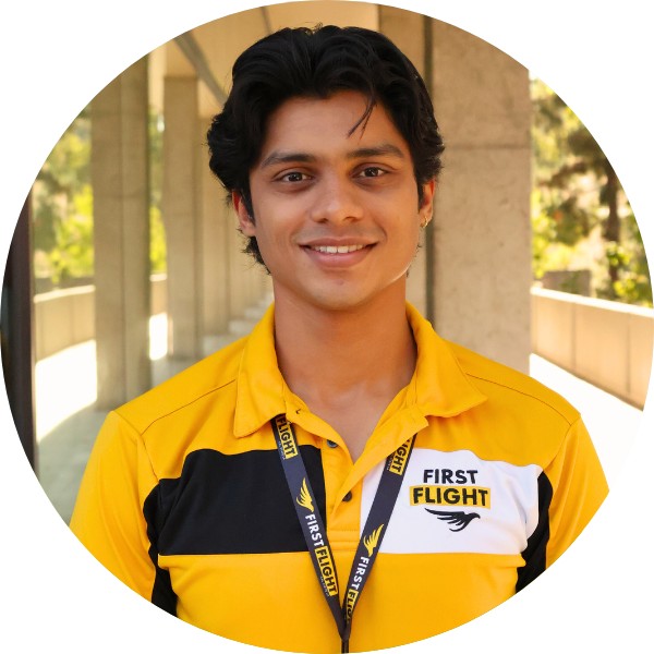 A man with a yellow and black polo that reads "First Flight" staring into the camera.