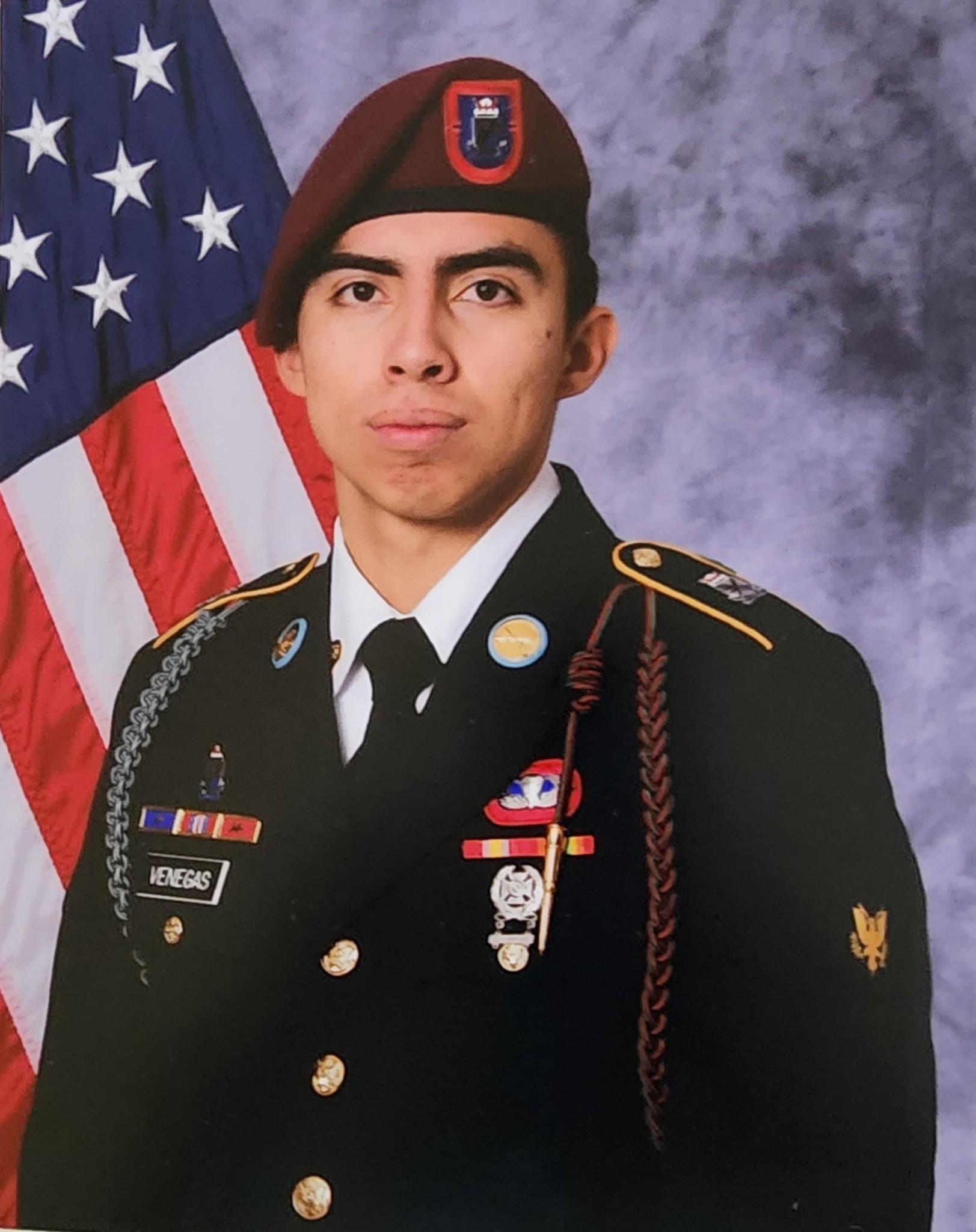 A person in a military uniform standing proudly in front of the American flag.