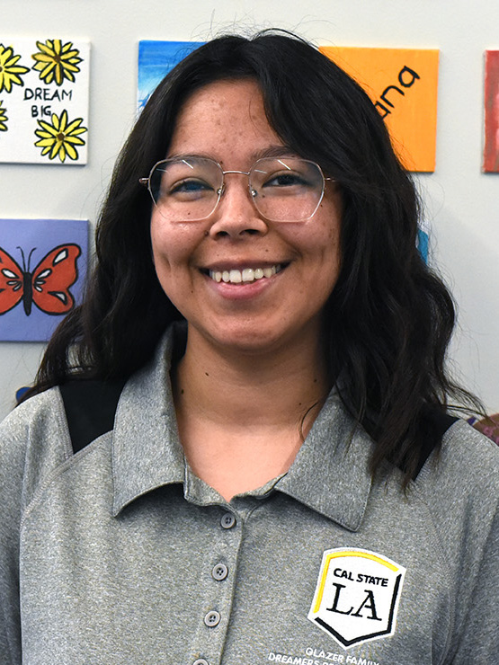 A person with medium length hair and glasses smiling