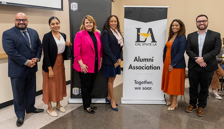 Group of people standing next to a banner that says Cal State L.A. Alumni Association