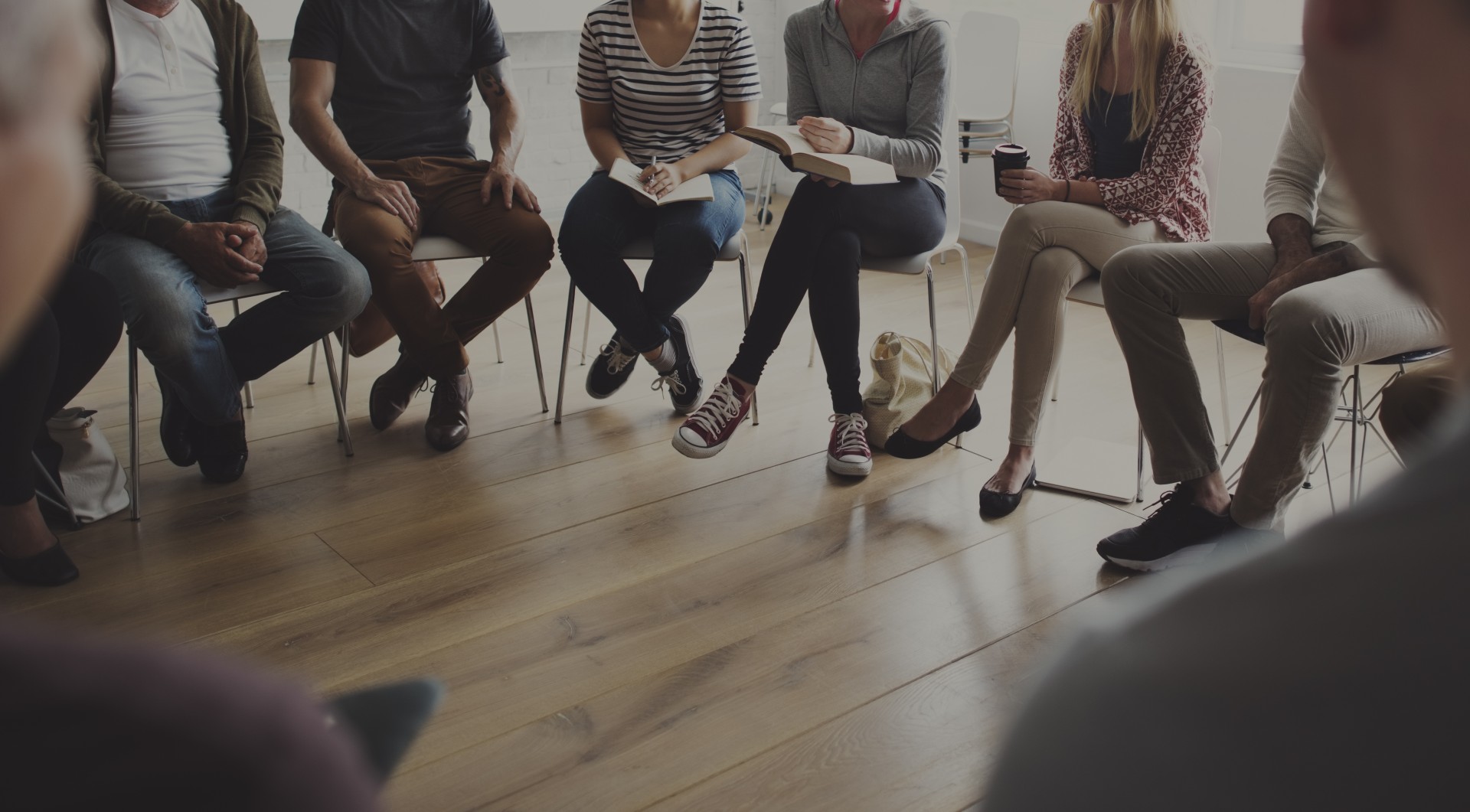 Group of people sitting on chairs in circle.