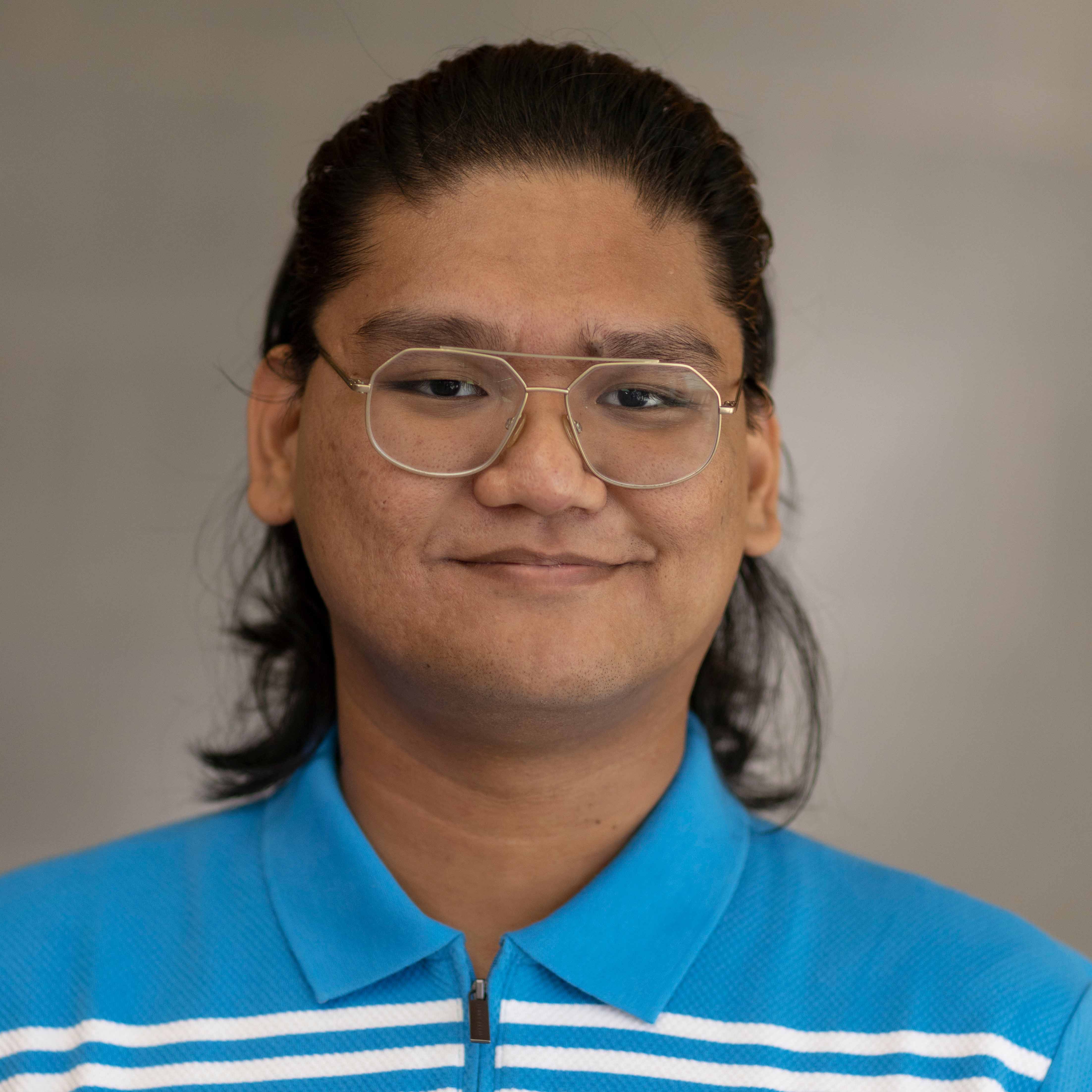 Alex Montenegro headshot. He is wearing glasses and a blue and white collared shirt