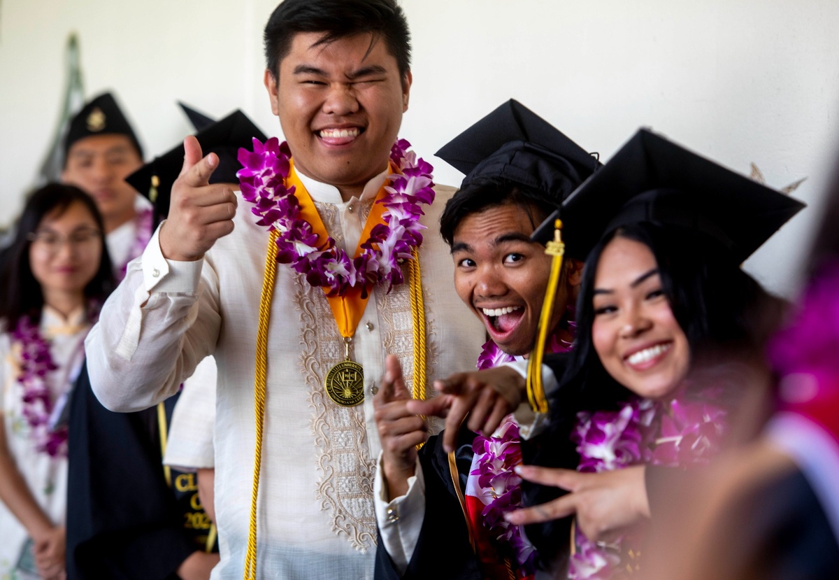 Cal State LA graduates wearing leis and caps smile and pose playfully for the camera during the APIDA graduation celebration.