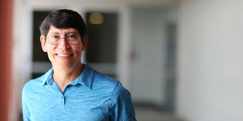 arturo in blue shirt near window smiling