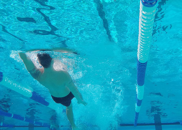 A swimmer swimming underwater in clear blue water.